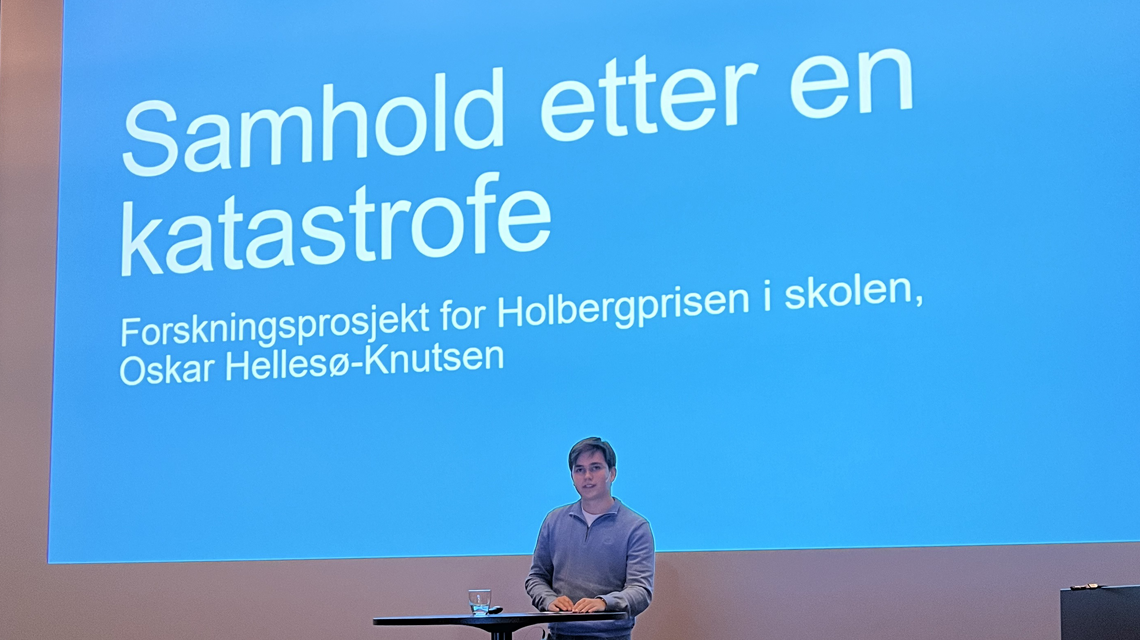 Oscar Hellesø-Knutsen presenterer med powerpoint i bakgrunnen.